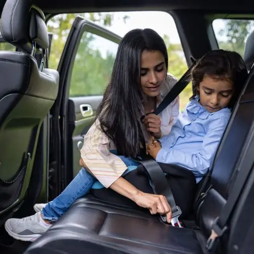 Mother securing her child in a professional car seat inside a luxury SUV for Orlando airport transportation