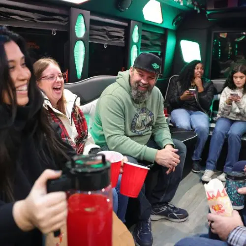 Group of friends laughing and enjoying drinks inside an Orlando party bus